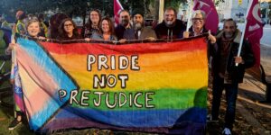 NDP leader Jagmeet Singh stands in the centre alongside union leaders holding a large Pride flag.