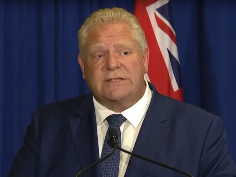 Doug Ford stands in front of a podium at a press conference.