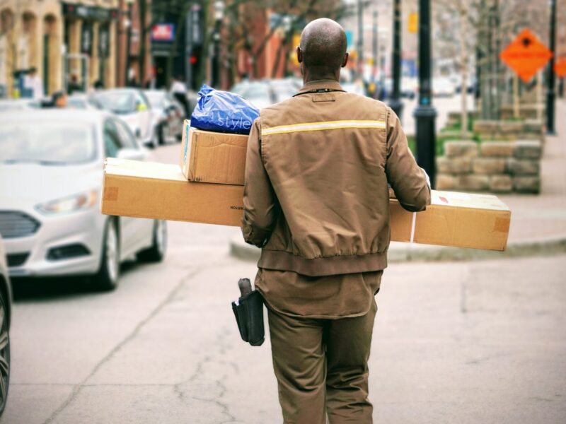 An image of a postal worker carrying packages. Postal workers represented by CUPW are speaking out against the punitive ways the Canada post promotes health and safety.