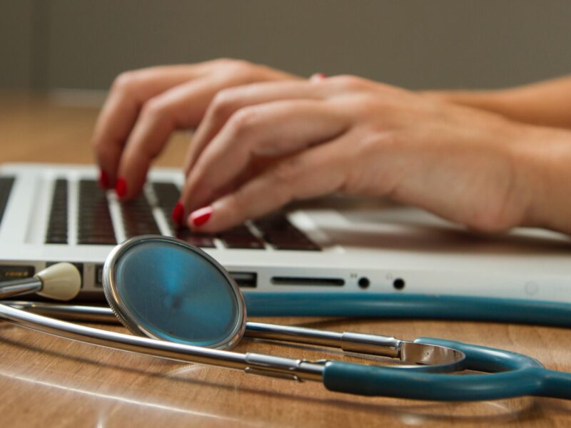 An image of someone typing on a laptop with a stethoscope laying next to them. Canada's largest nurses' union is partnering with Queen's University to study the impact of agency nurses.