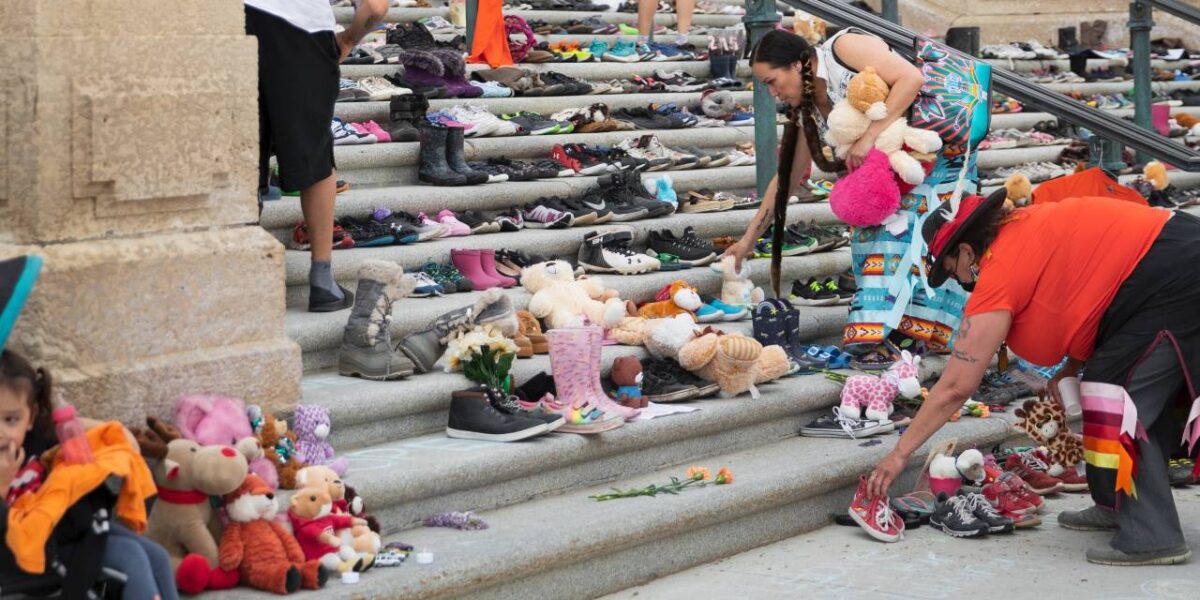 Indigenous women placing stuffed animals on the steps of a government building in Regina, Saskatchewan.