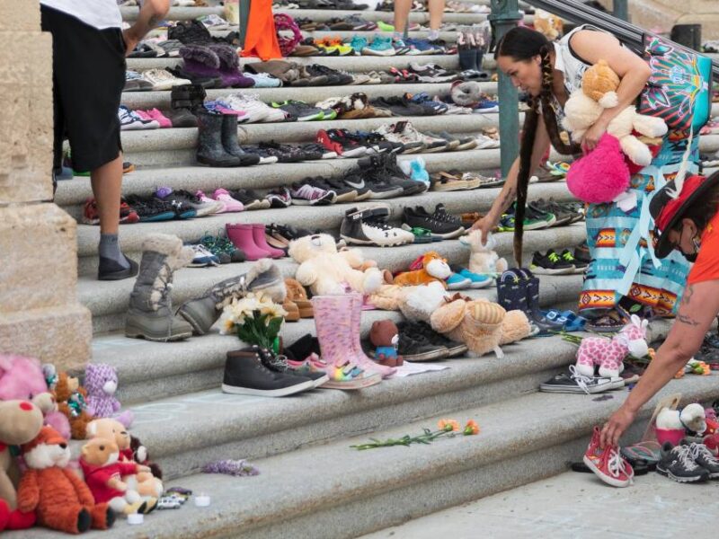 Indigenous women placing stuffed animals on the steps of a government building in Regina, Saskatchewan.
