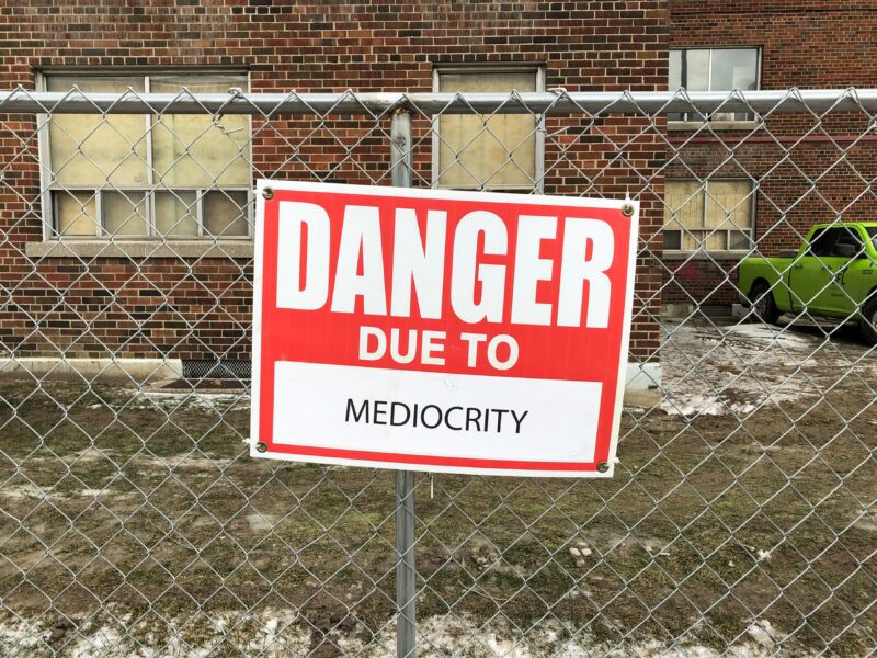 A sign which says "Danger due to mediocrity"