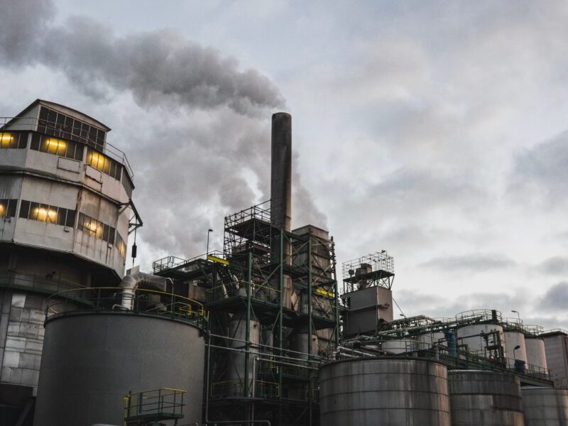 An image of an industrial building pumping smoke into the air. Corporations must be held accountable for their role in the climate crisis.