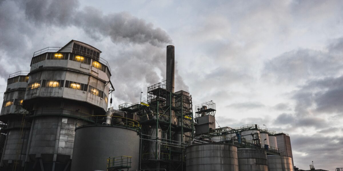 An image of an industrial building pumping smoke into the air. Corporations must be held accountable for their role in the climate crisis.