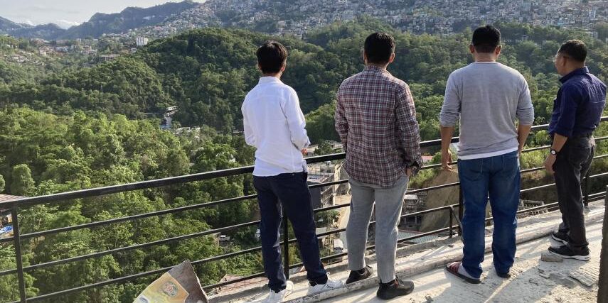 An image of a group of media and news workers on a mountain, looking onto the valley.