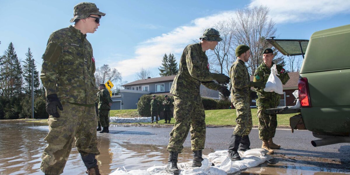 Canadian Armed Forces members placing sand bags to stop flood waters.