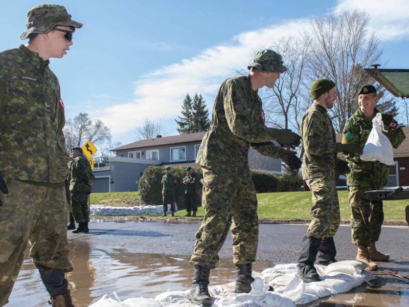 Canadian Armed Forces members placing sand bags to stop flood waters.