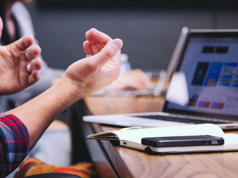 A person gesturing with their hands at a boardroom table.