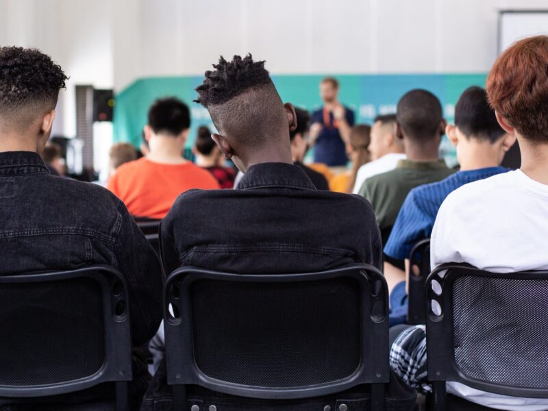 An image of three children sitting in a lecture. They are facing away from the camera.