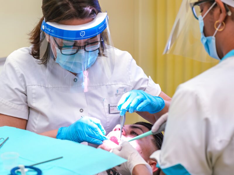 An image of some dentists working on a patient. Recent Statistics Canada data indicates amount of Canadians who have dental care is decreasing.