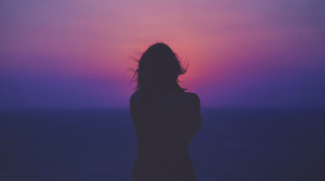 A woman facing a sunset.