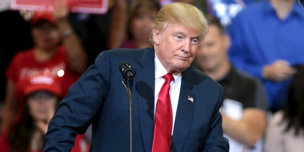 Former US President Donald Trump stands at a podium at a rally.