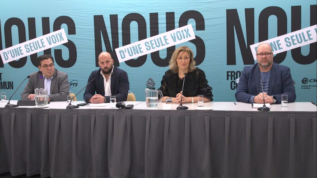 Four leaders of the Front commun sit at a table during a press conference.