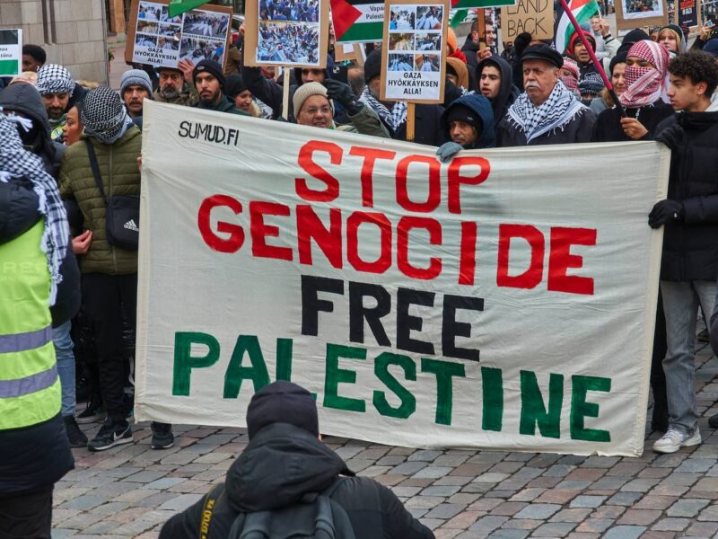 Demonstrators hold a banner reading "Stop Genocide: Free Palestine."