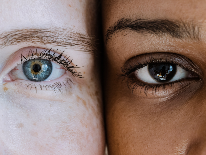 A white person and a Black person side by side, close up on faces, eyes.