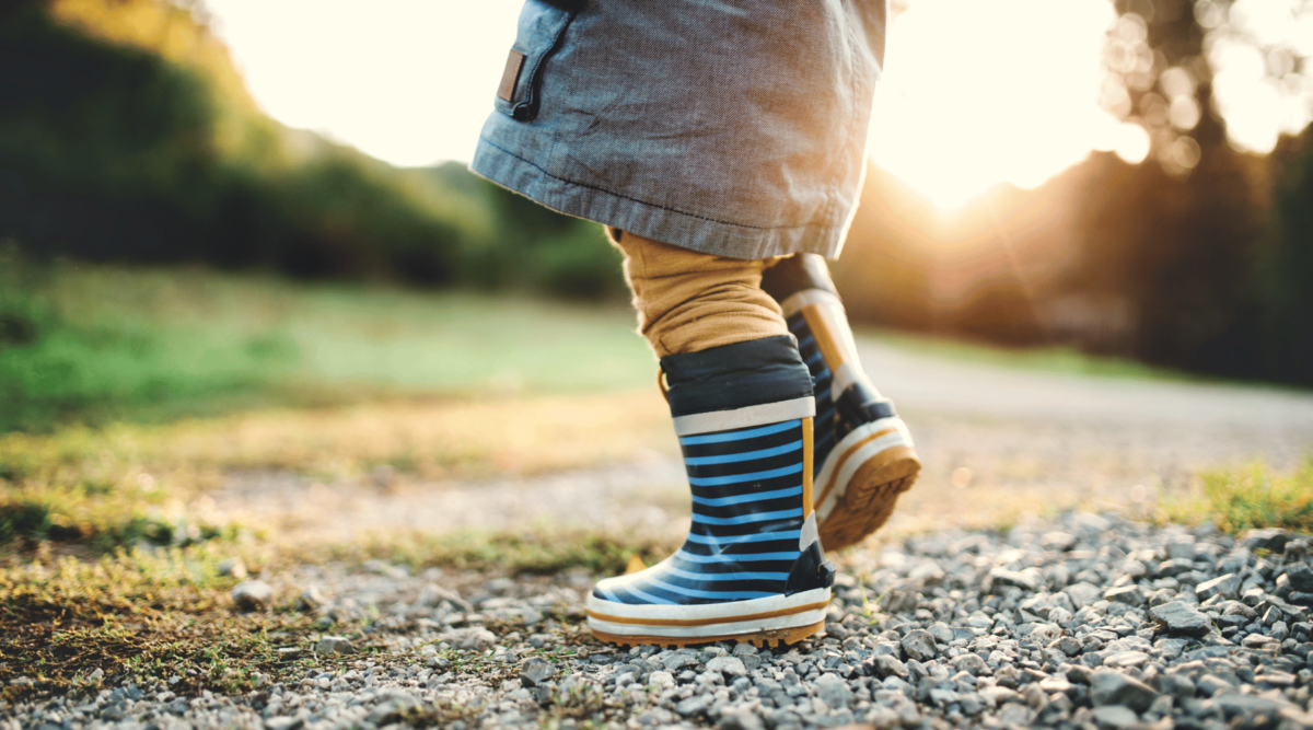 A photo of a small child's legs, walking outside.