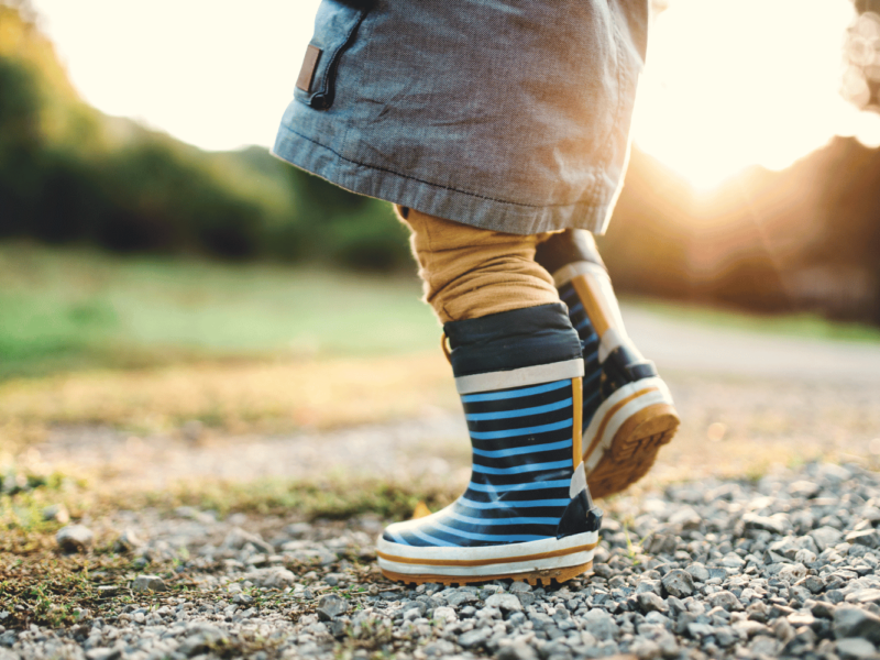 A photo of a small child's legs, walking outside.