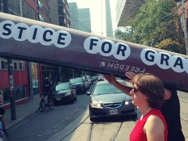 People carrying a canoe reading "Justice for Grassy."