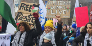 Women at the 2024 International Women's Day march holding signs in support of the Palestinian women of Gaza.
