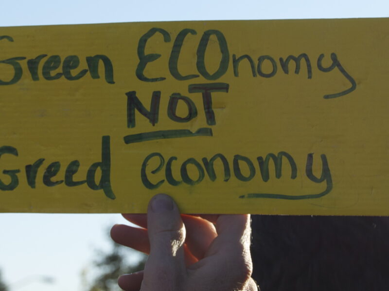 A yellow sign that reads "Green ECOnomy not greed economy."