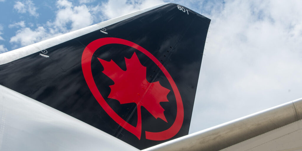 The tail fin of an Air Canada plane featuring their logo.