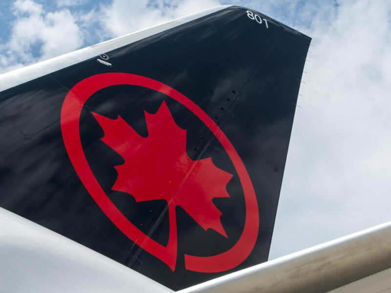 The tail fin of an Air Canada plane featuring their logo.