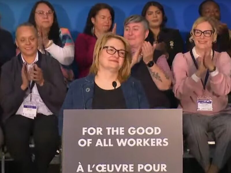 Canadian Labour Congress president Bea Bruske makes a speech on April 18 with labour leaders applauding behind her.