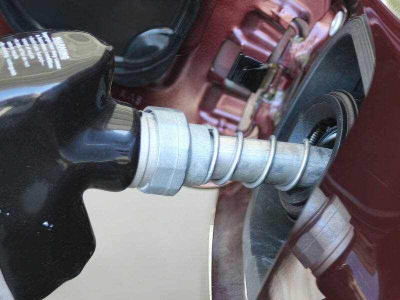 A person putting gas in their car from a pump station.