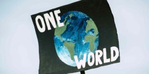 A photo of an Earth Day protest sign showing the globe with the words "One World" written on it.