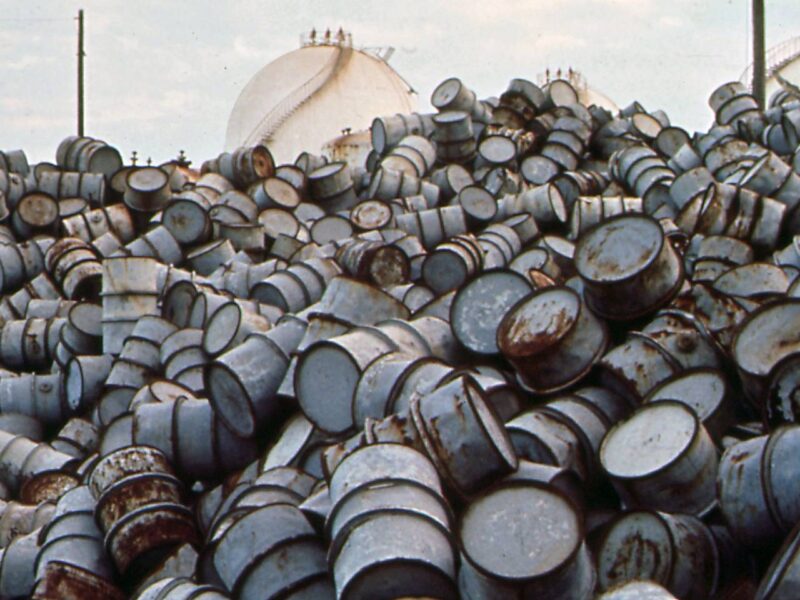 A photo taken in 1972 of a pile of damaged oil drums near the Exxon Mobile facility in Baton Rouge, Louisiana, part of the decades long history of corporations poisoning those living in what is now Cancer Alley.
