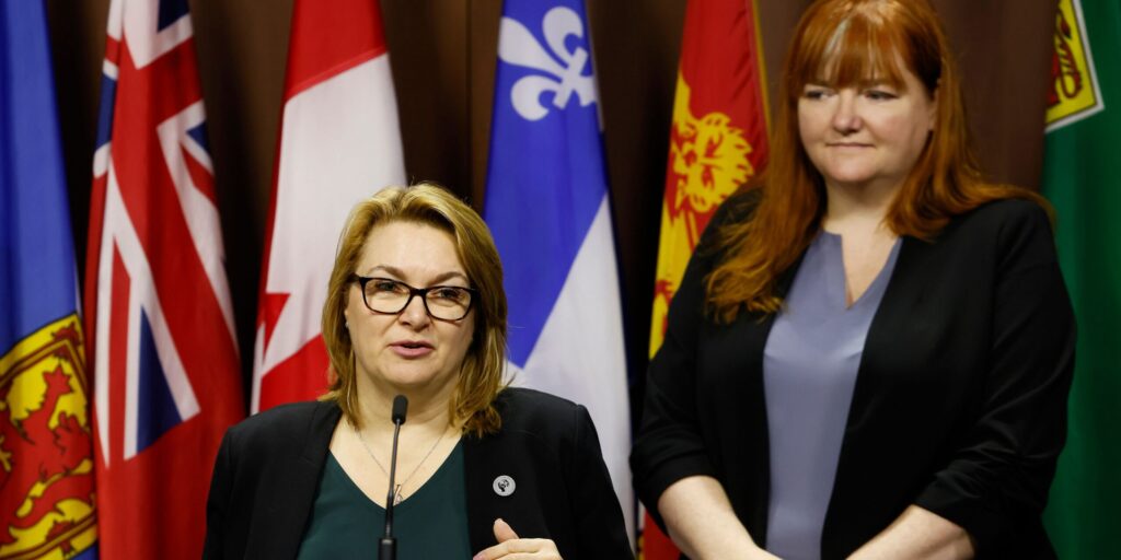 CLC president Bea Bruske speaking at a podium with executive vice president of the Canadian Labour Congress Siobhán Vipond standing behind her.