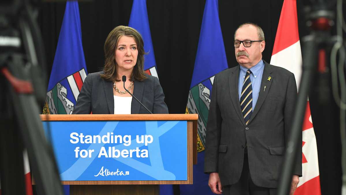 Alberta Municipal Affairs Minister Ric McIver stands by obediently as Premier Danielle Smith.