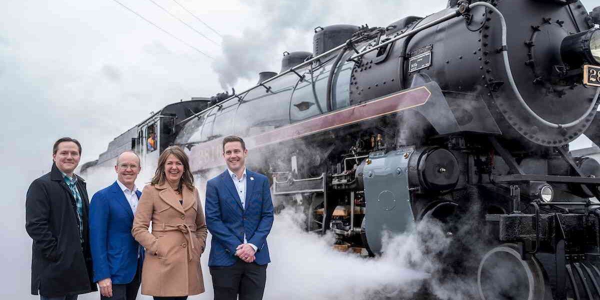 Alberta Premier Danielle Smith standing in front of a steam train with some of her cabinet ministers.