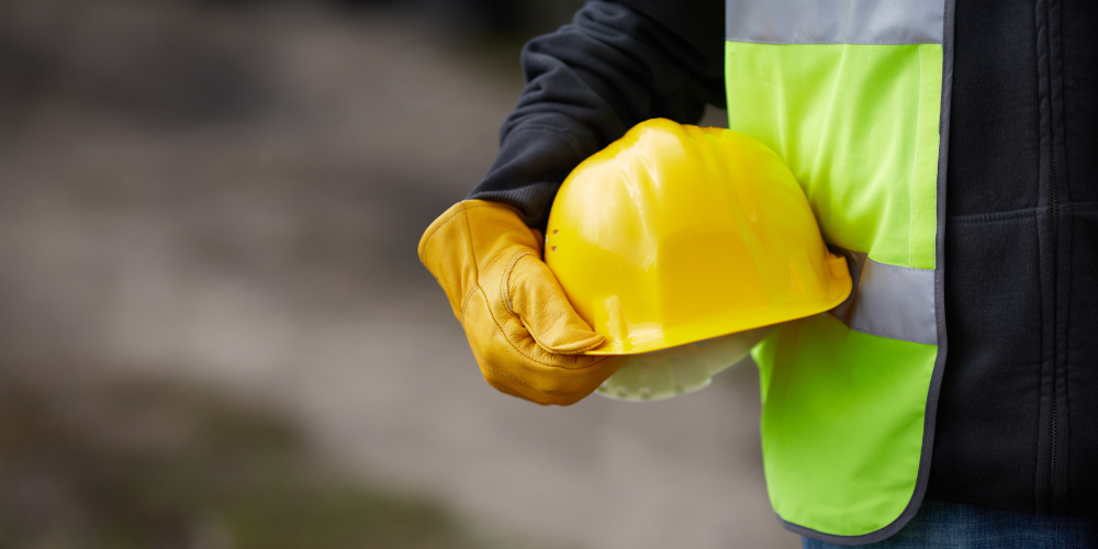 A person in a safety vest holding a safety hat.