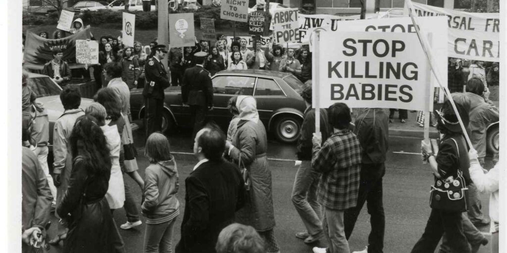 Police vehicles separate supporters and opponents of abortion rights marching in Toronto (10 May 1981).