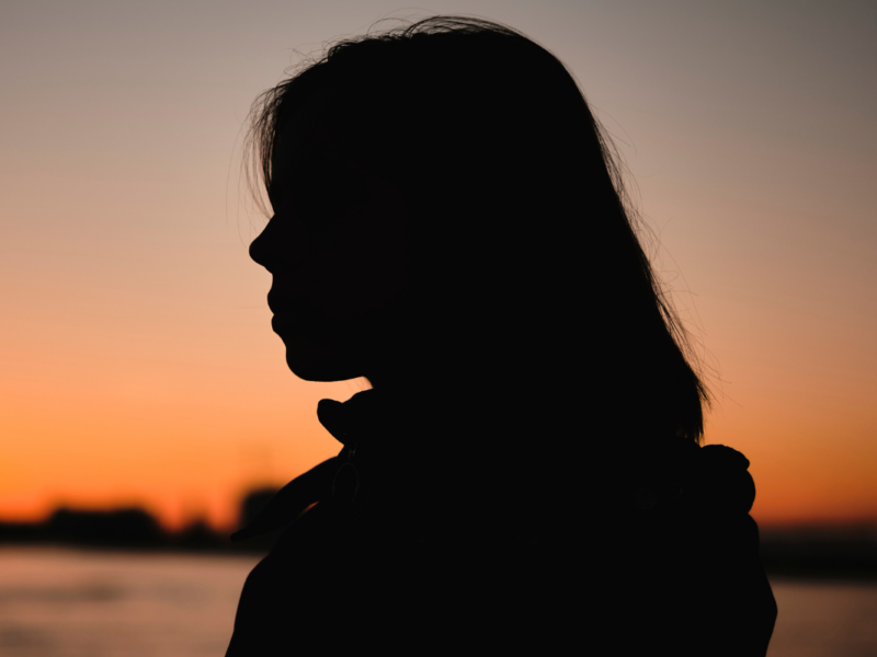 The silhouette of a woman as the sun sets in the background.