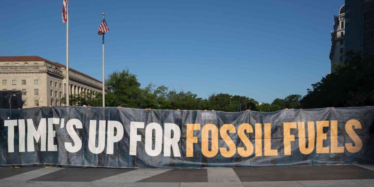 Protesters holding up a sign calling for the end to fossil fuels.