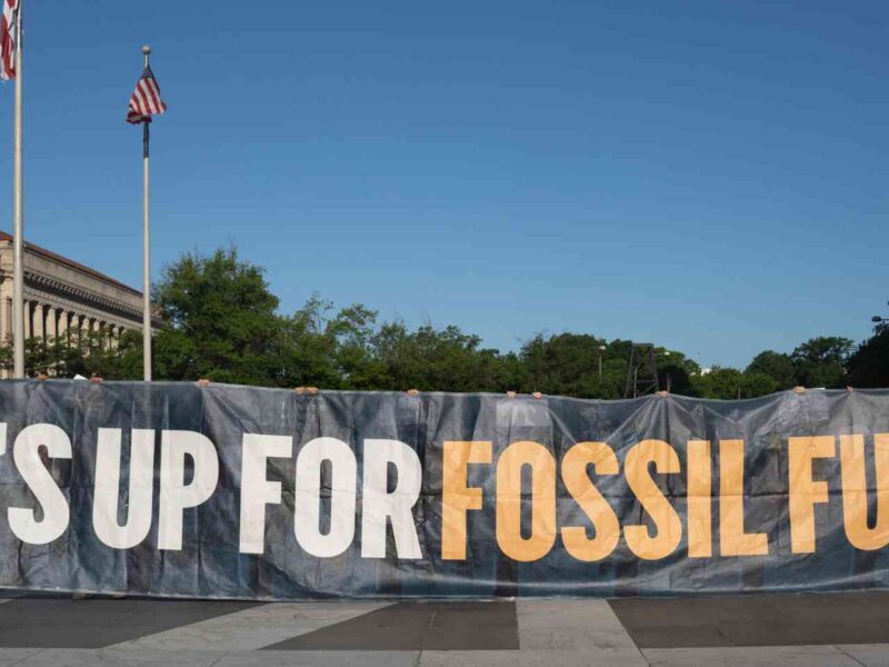 Protesters holding up a sign calling for the end to fossil fuels.