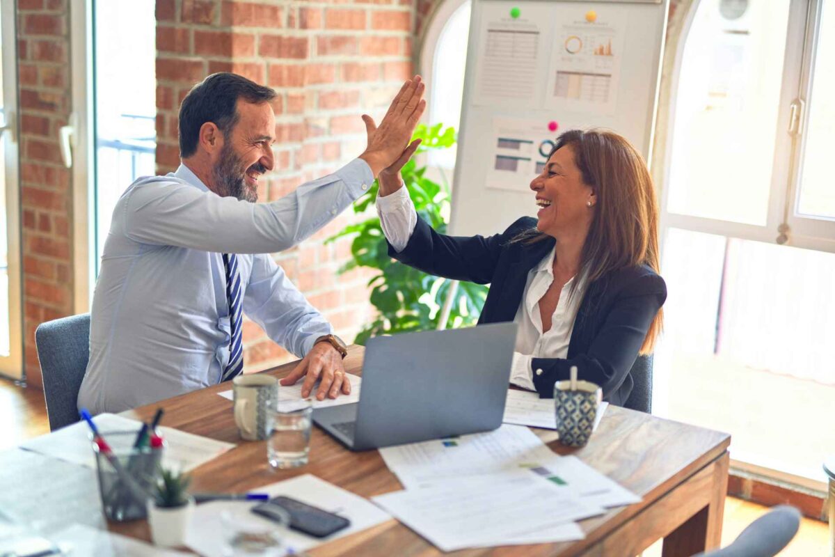 Two people in business attire give each other a high five.