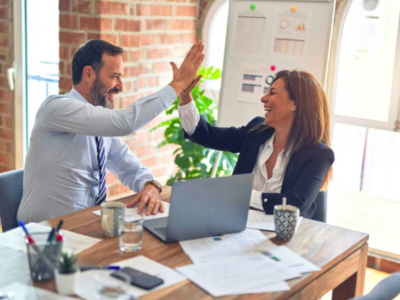 Two people in business attire give each other a high five.