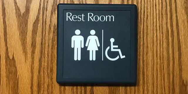 An image of a rest room sign on a wooden door.