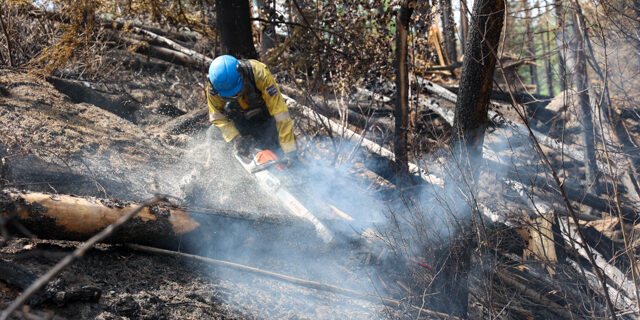 A Parks Canada employee works to clear debris after the Jasper wildfire.