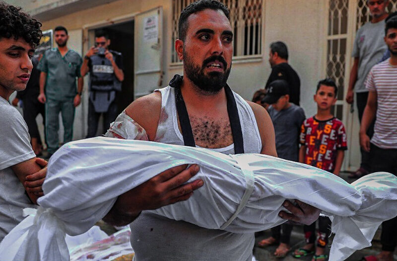 A Palestinian man carrying the body of a child in Gaza in October of 2023.