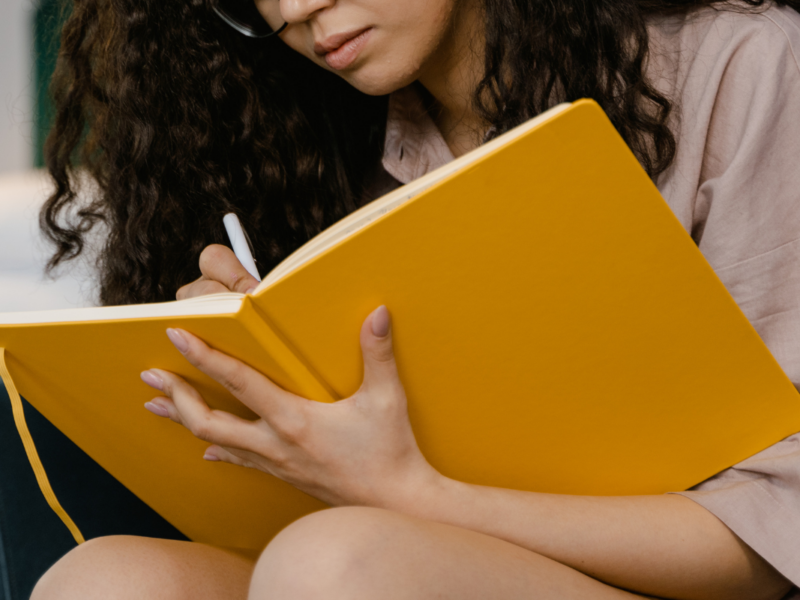 A person holding a large yellow notebook.