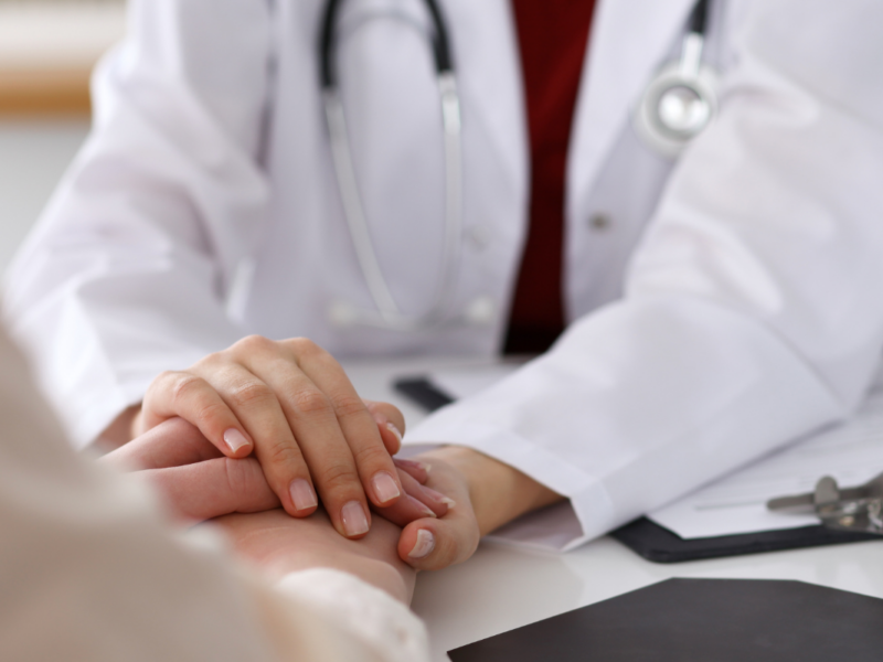 A doctor holding the hand of a patient.