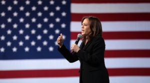 Kamala Harris speaking at a rally in front of an American flag.