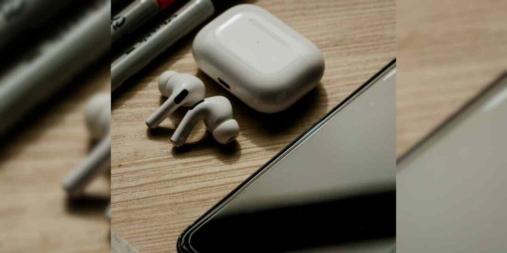 A cellphone on a desk along with earbuds and markers.