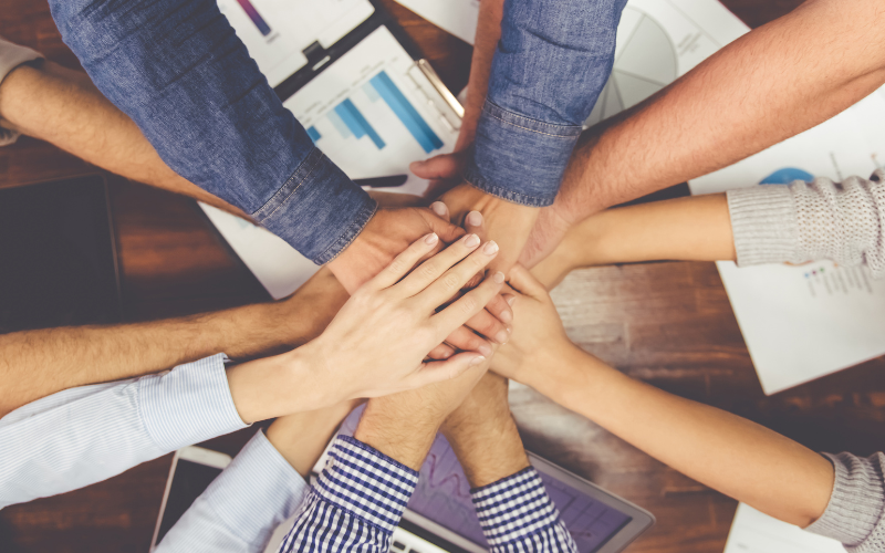 A group of people with hands in a centre.