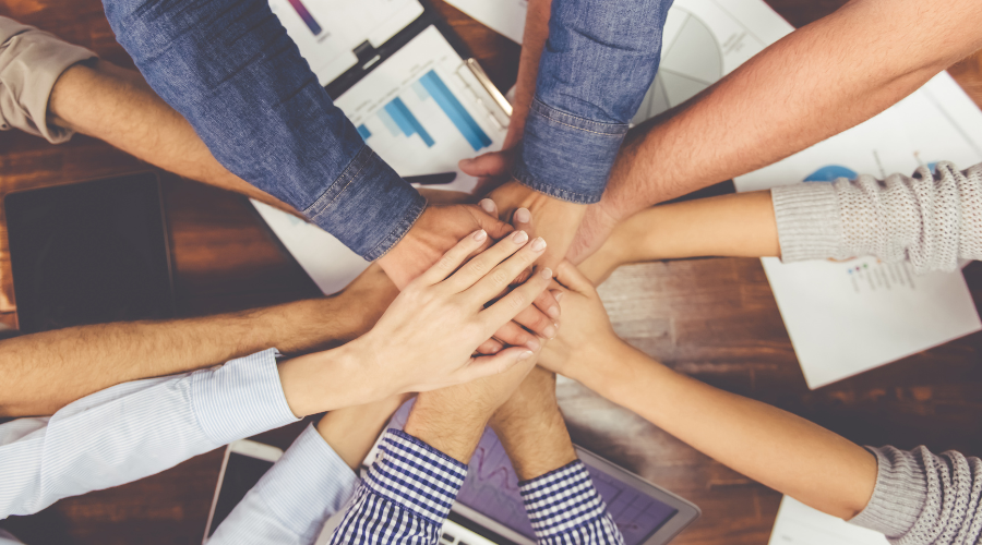 A group of people with hands in a centre.